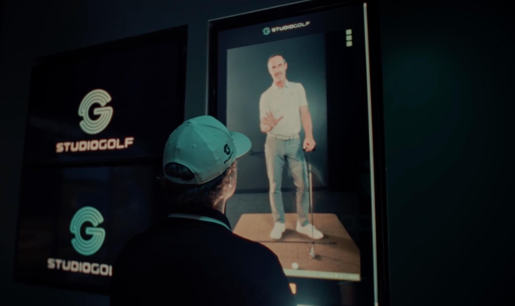 Golfer interacting with Studio Golf’s in-bay touchscreen drill system, reviewing personalized practice plans and swing comparisons.