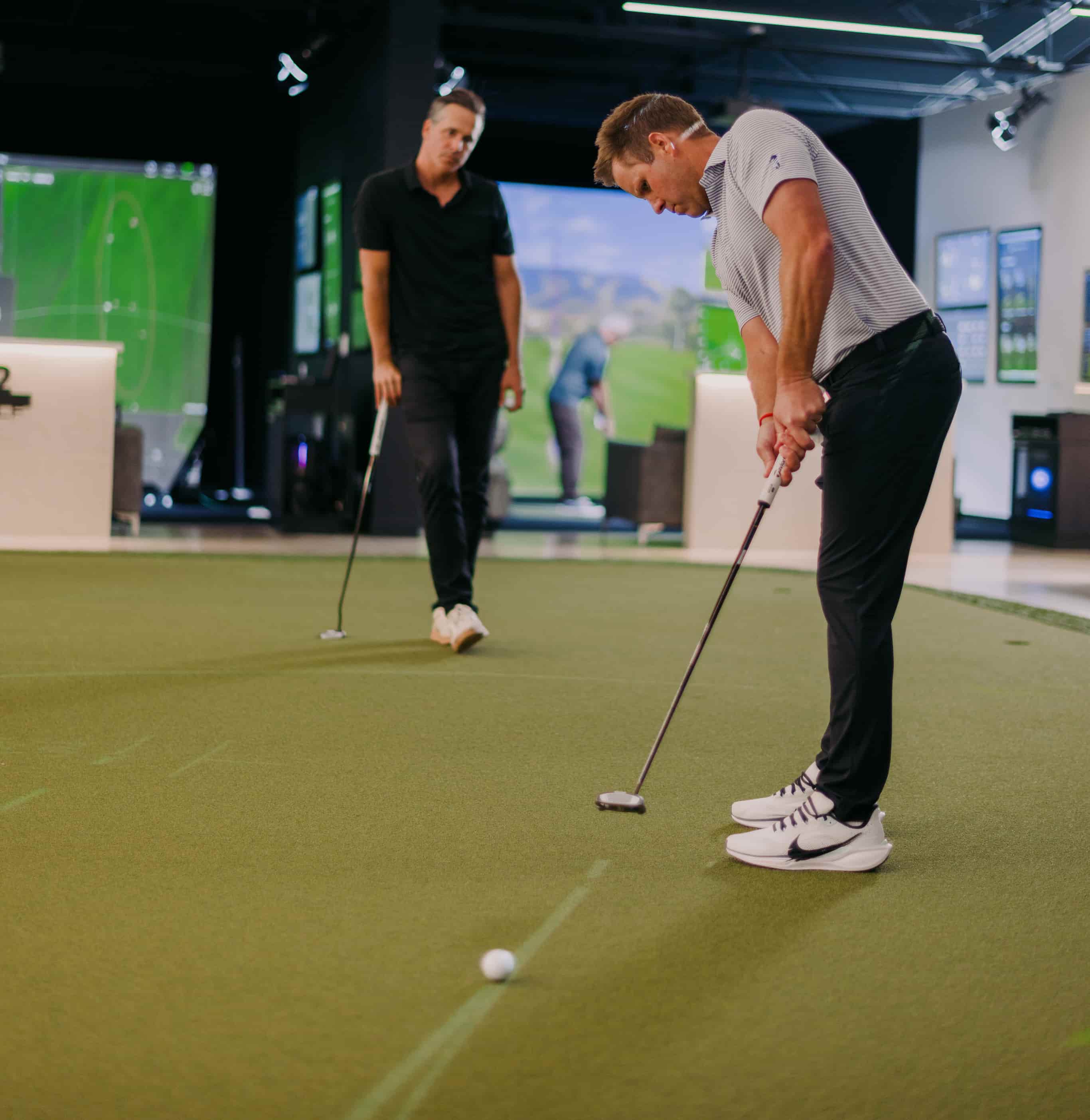 Members rolling putts on the putting green at Studio Golf